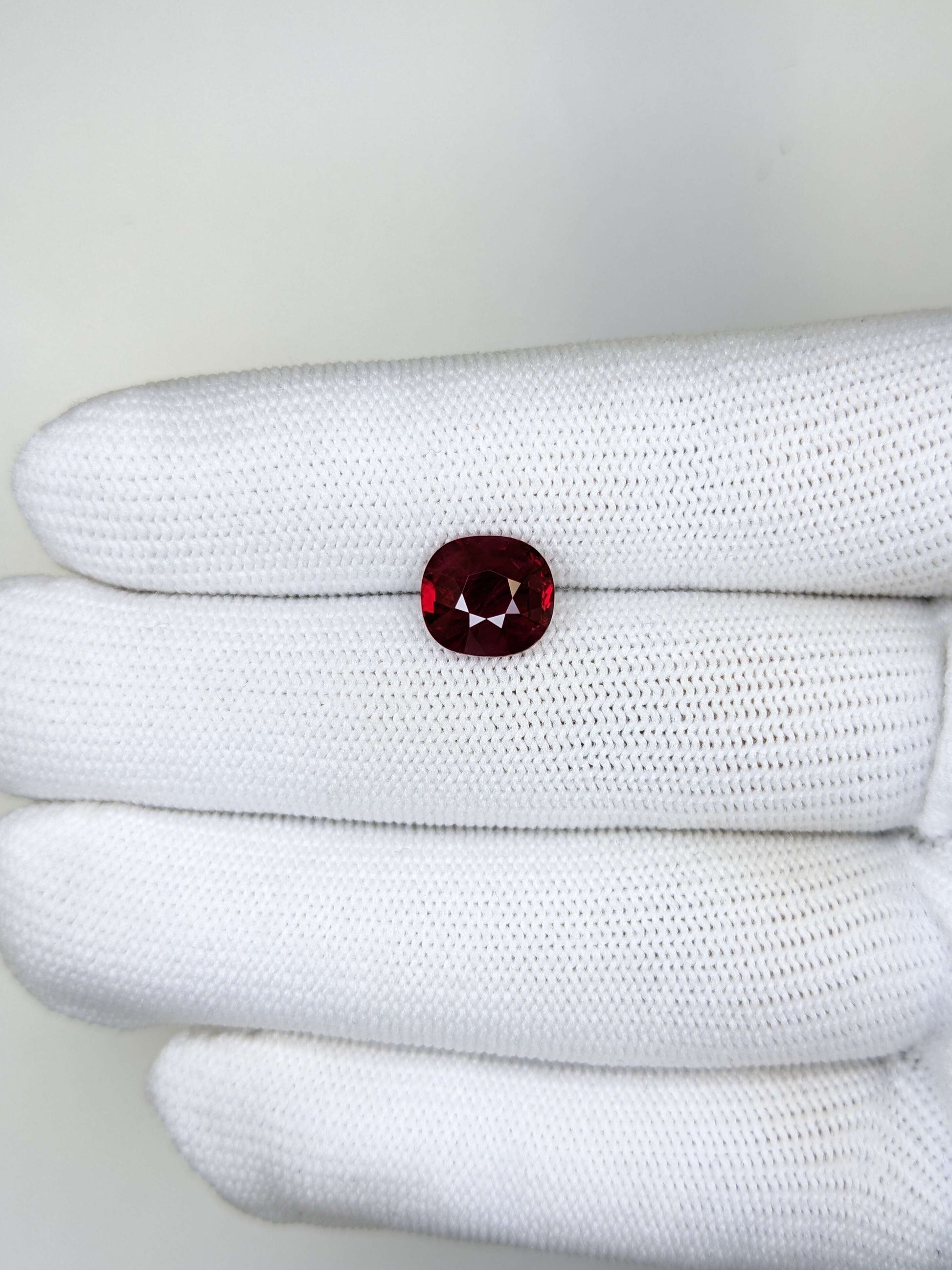 White glove with a red gemstone on a white background