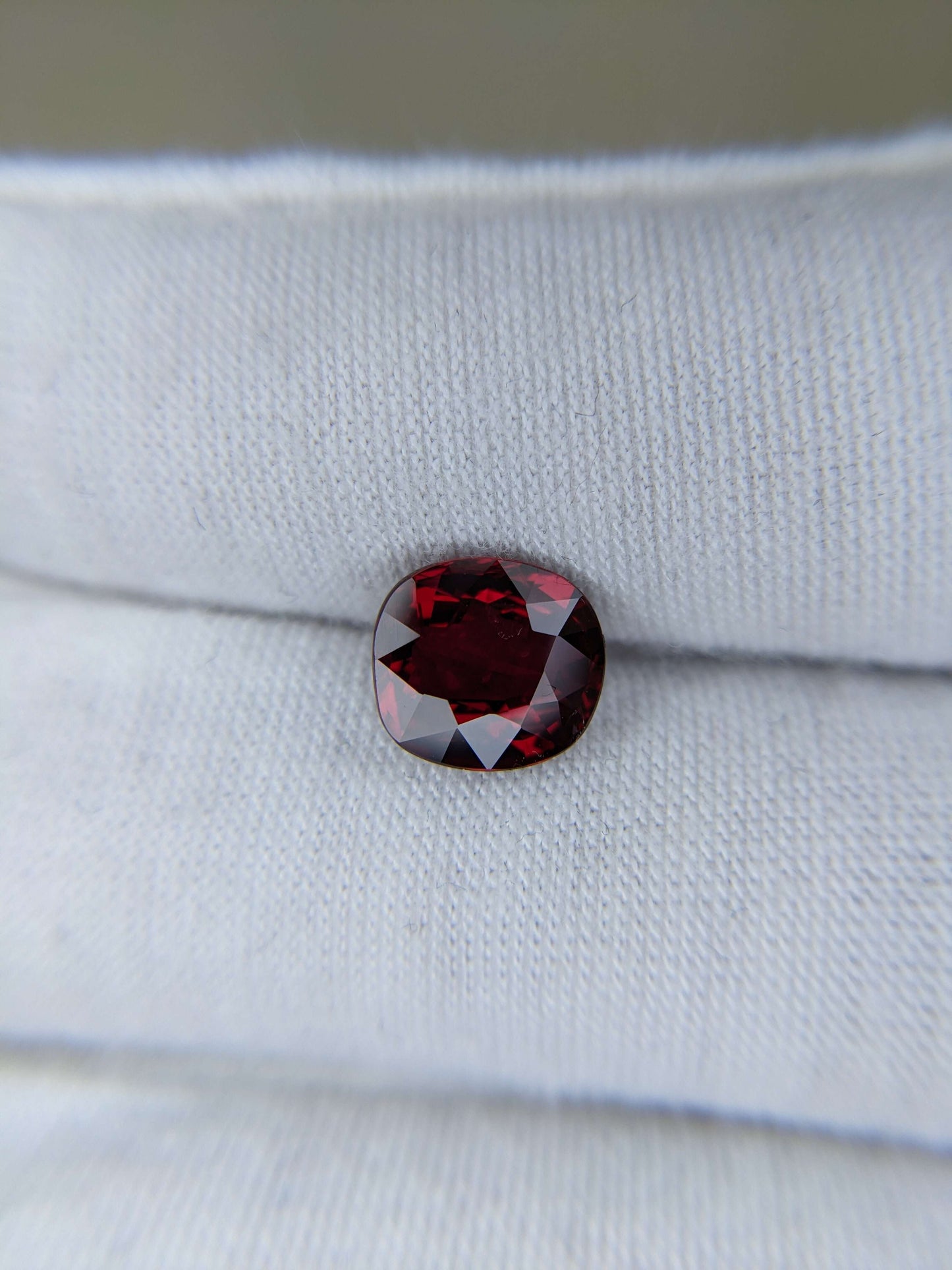 Red ruby cushion cut loose gemstone on a white fabric background