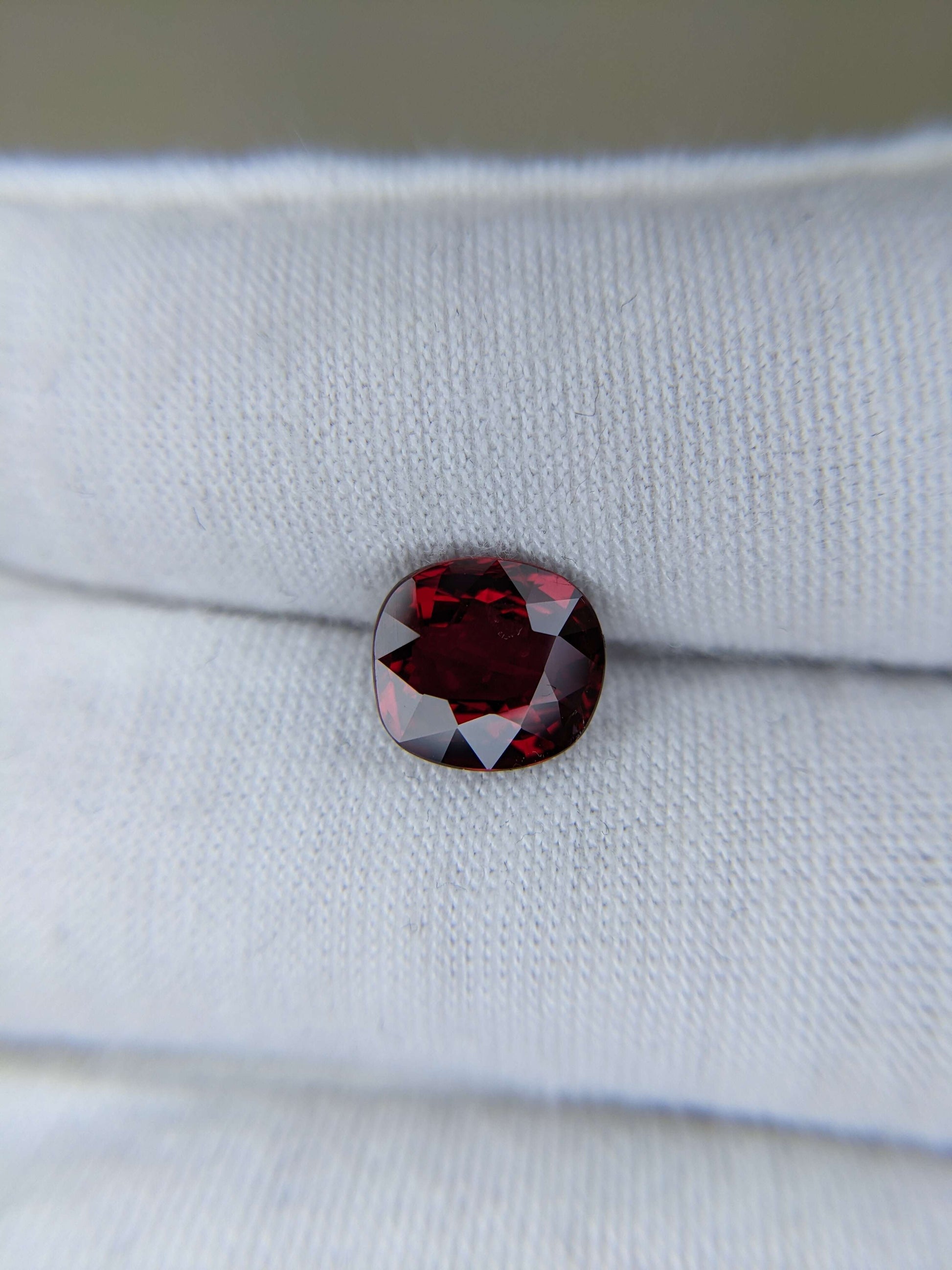 Red ruby cushion cut loose gemstone on a white fabric background