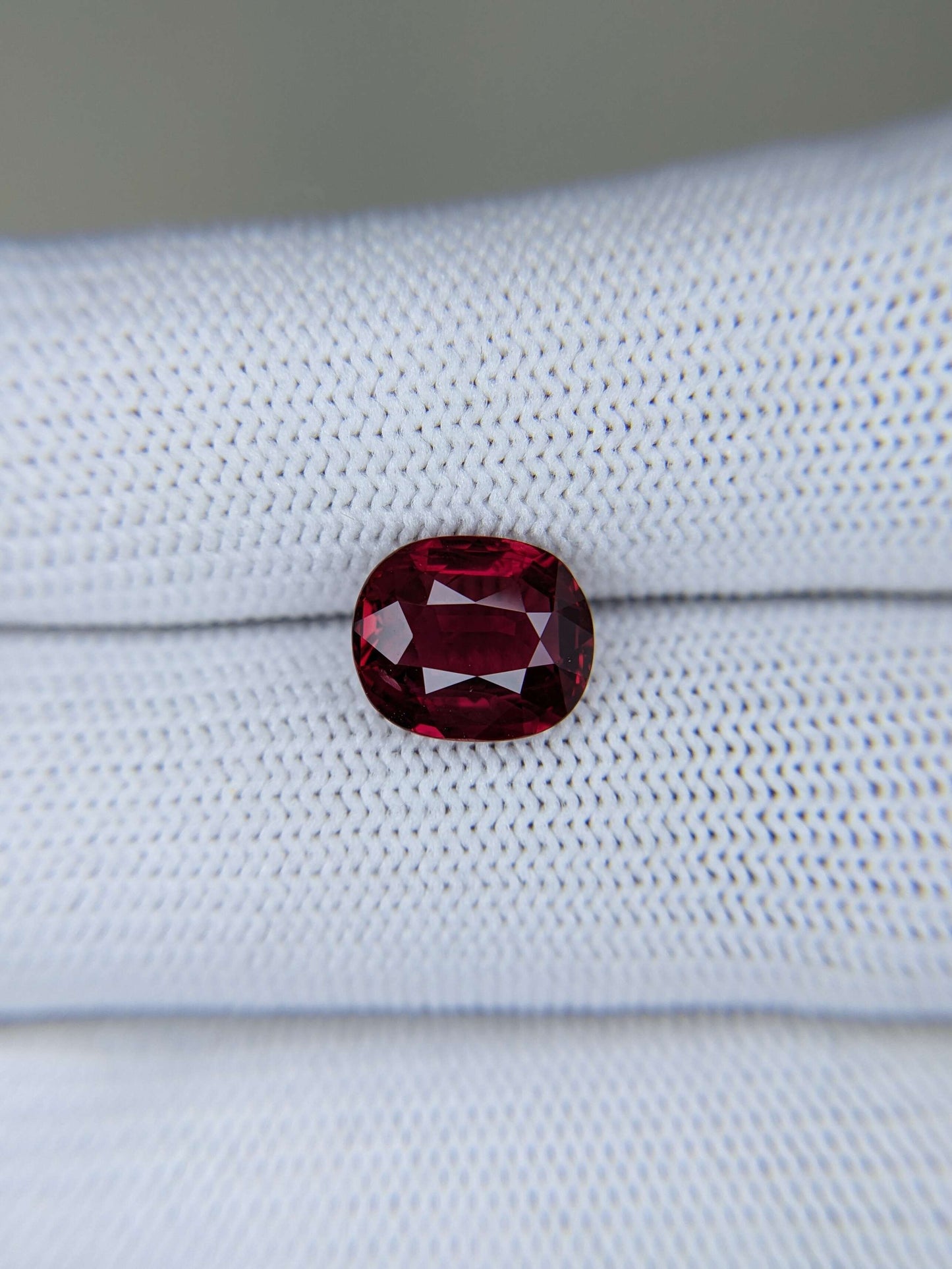Red gemstone on a light gray fabric background