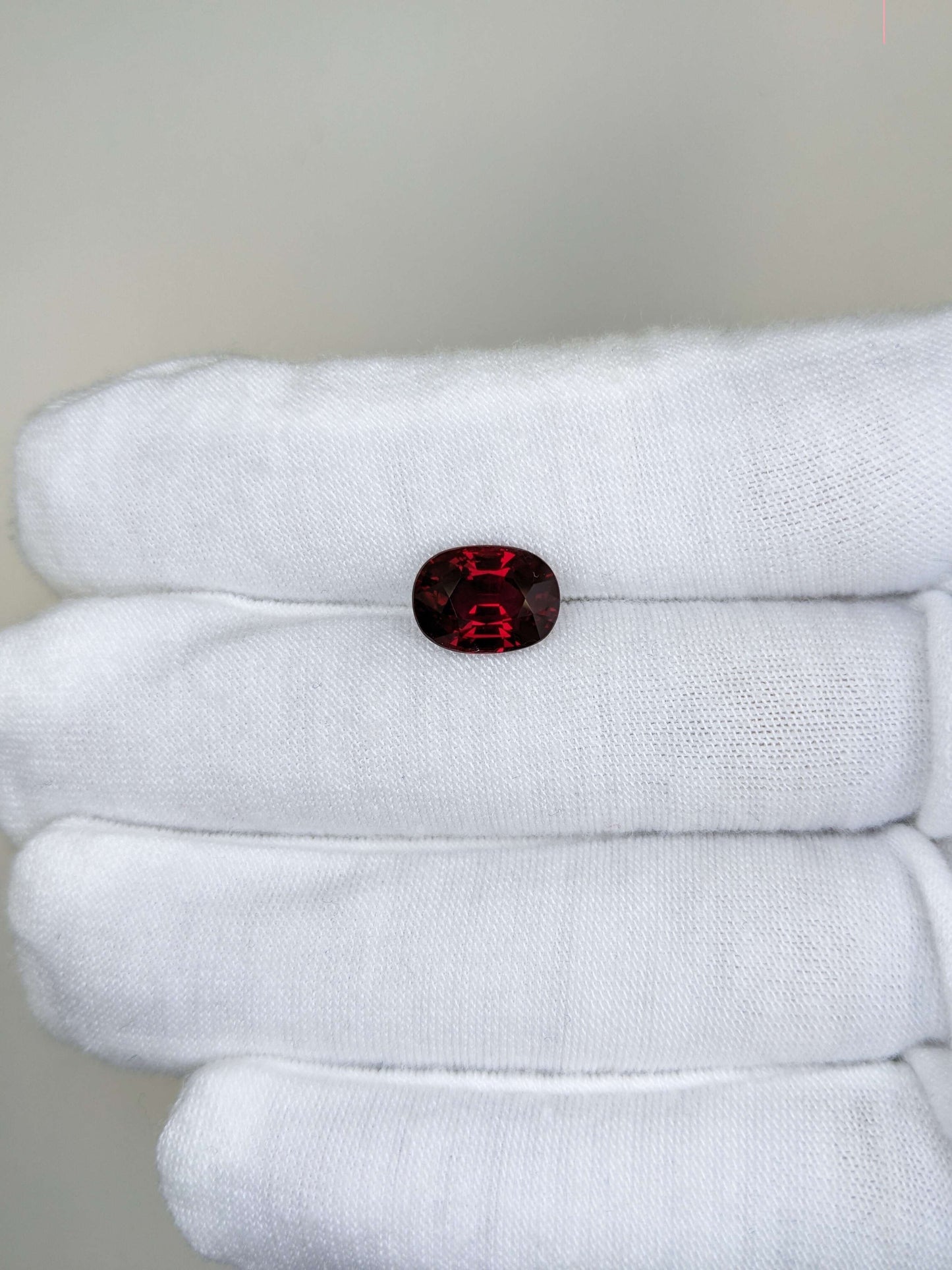 Red ruby gemstone on a white cloth with a neutral background
