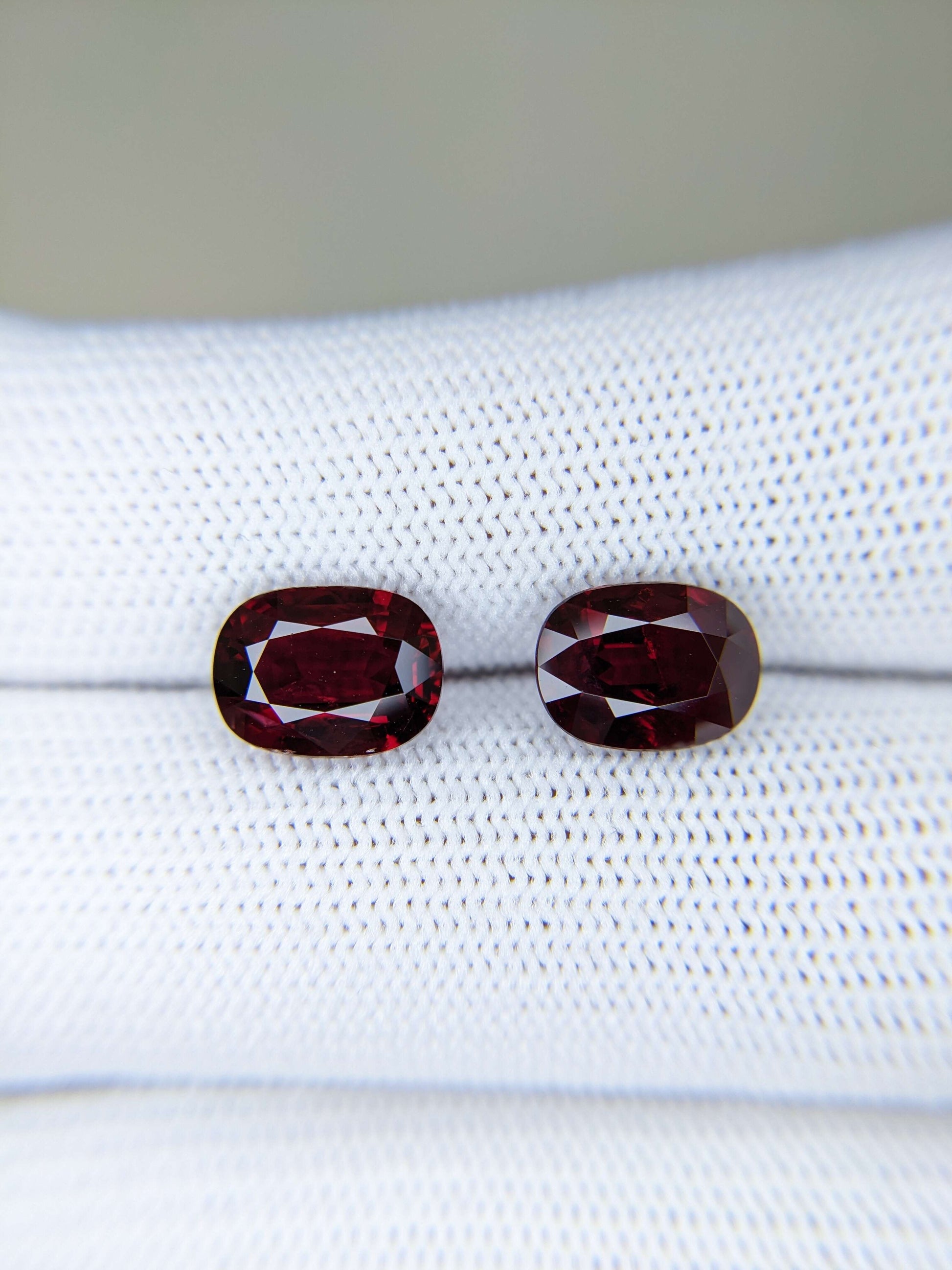 Two red gemstones on a white cloth background