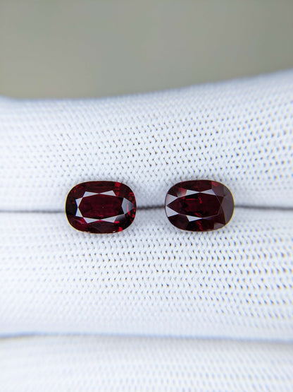 Two red gemstones on a white cloth background