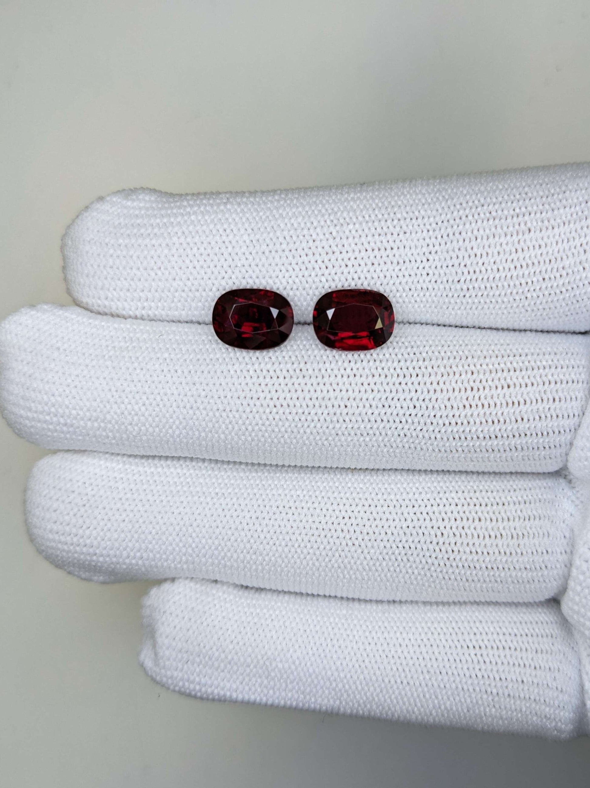 Two red gemstones on a white cloth background