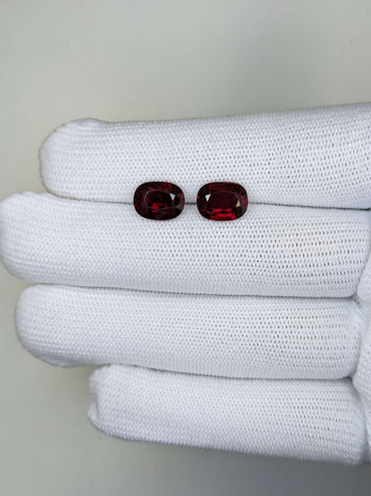 Two red gemstones on a white cloth background