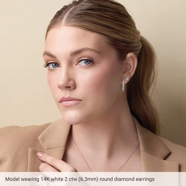 Woman wearing 14K white gold diamond earrings against a beige background