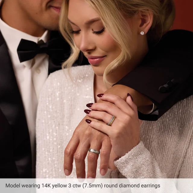 Woman wearing 14K yellow gold round diamond earrings with a man in formal attire.