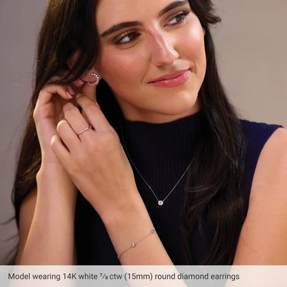 Woman wearing 14K white gold round diamond earrings with a neutral background