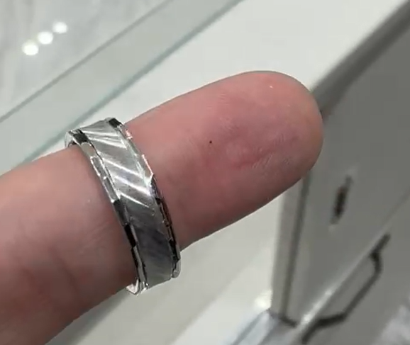 Silver ring on a finger with a neutral background