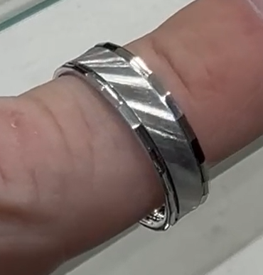 Silver bracelet on a finger with a plain background