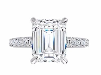 Diamond ring with emerald-cut center stone on a white background