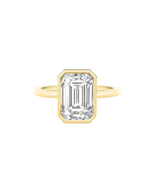 Gold ring with an emerald cut diamond on a white background