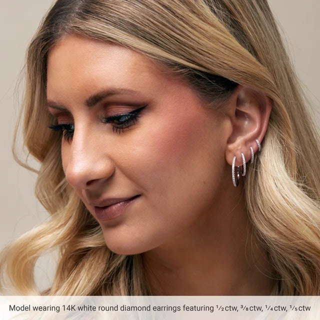 Close-up of a woman wearing 14K white round diamond earrings with text indicating earring details.