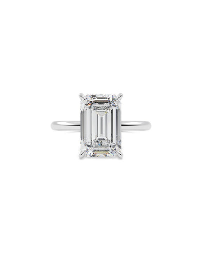 Diamond ring with emerald-cut gemstone on a white background