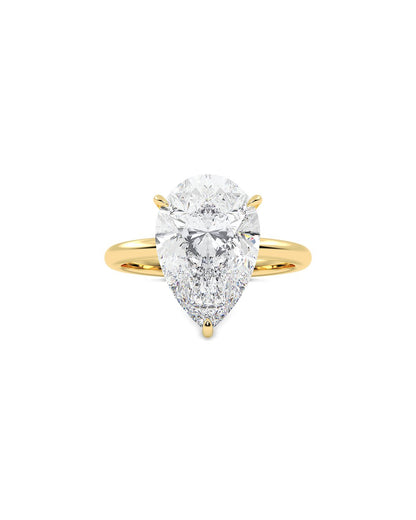 Gold ring with a pear-shaped diamond on a white background