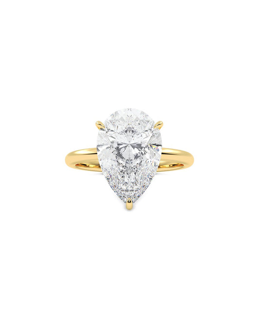 Gold ring with a pear-shaped diamond on a white background
