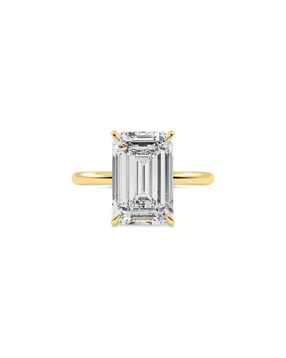 Gold ring with a large emerald-cut diamond on a white background