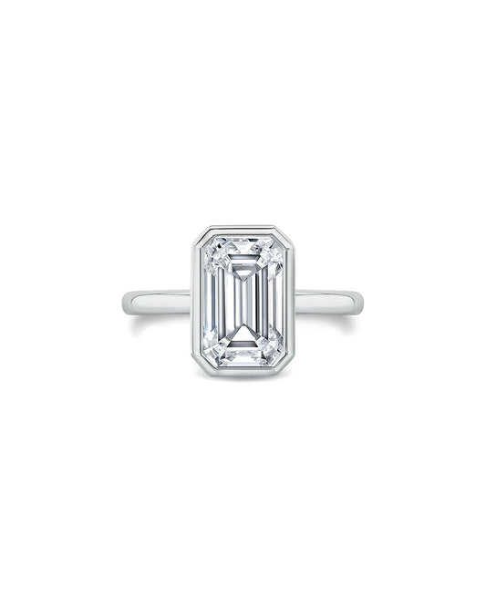 Diamond ring with emerald-cut gemstone on a white background