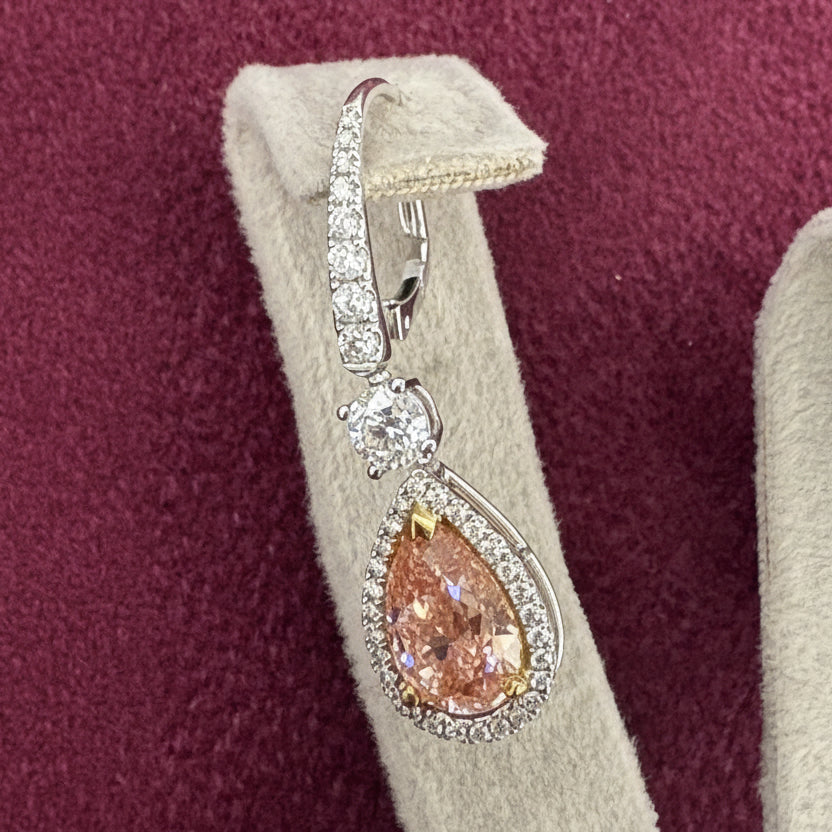 Diamond earring with teardrop-shaped pink gemstone on a display stand