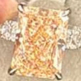 Diamond earring on a display stand with a hand holding it, against a red background.