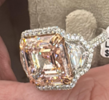 Diamond ring held in hand with price tag showing price.