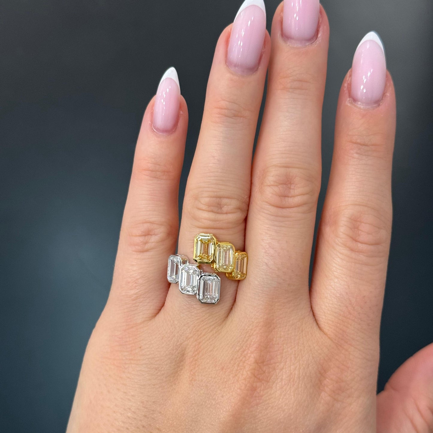Hand wearing two diamond rings with a dark background
