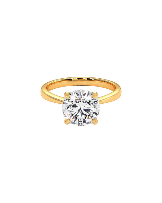 Gold ring with a clear round cut diamond on a white background