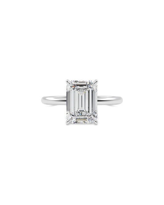 Diamond ring with emerald-cut gemstone on a white background