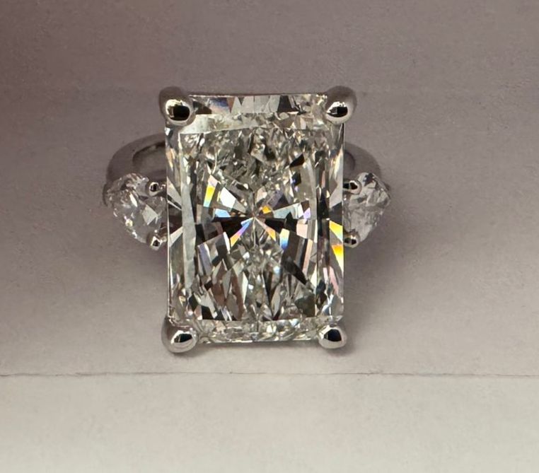 Diamond ring with a radiant cut stone and pear cut three stone on a gray background