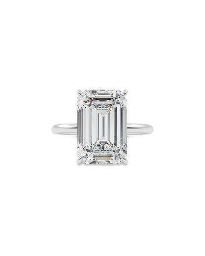 Diamond ring with emerald-cut center stone on a white background