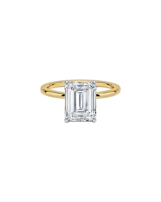 Yellow gold ring with an emerald cut diamond on a white background
