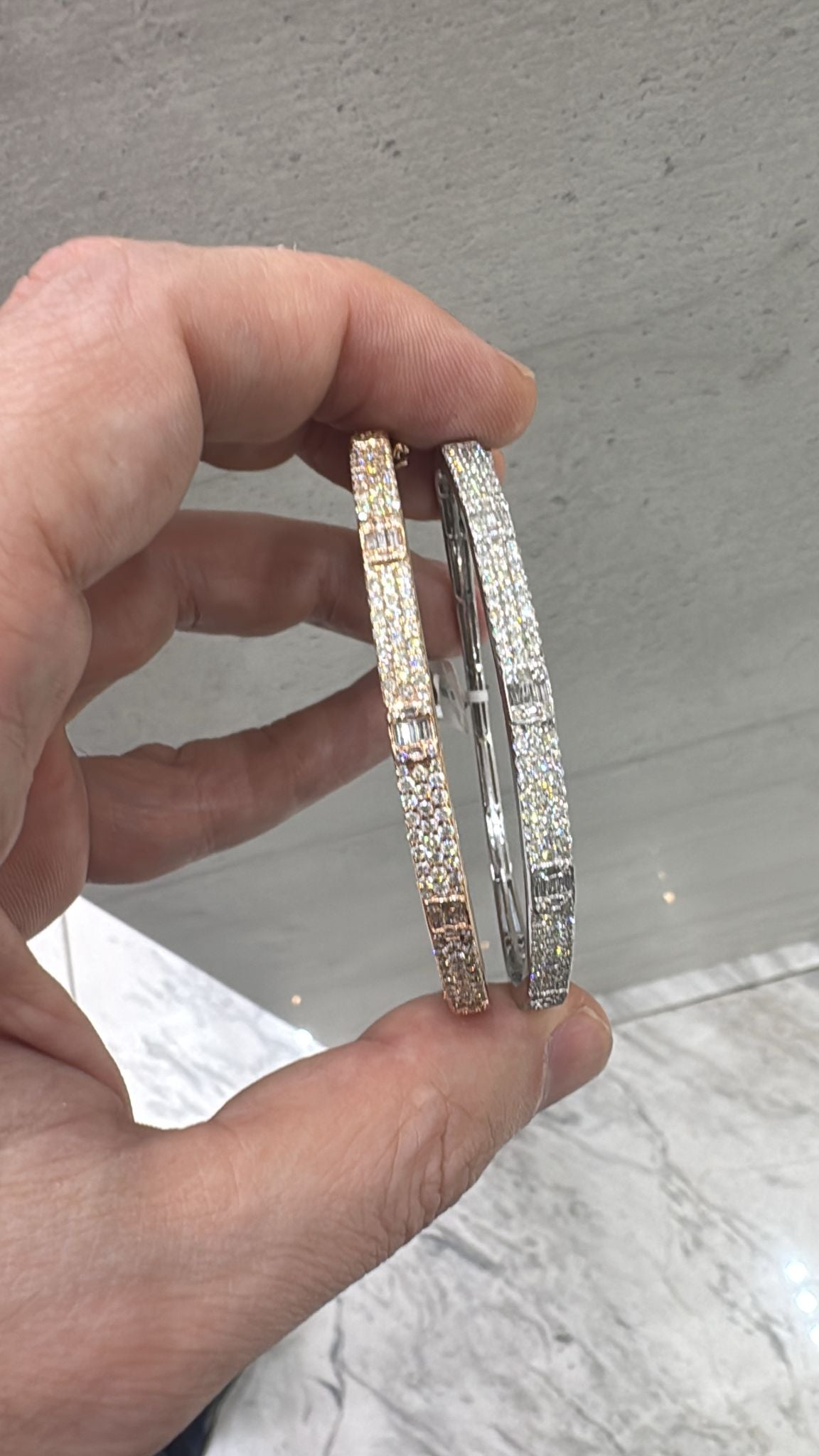 Hand holding two sparkling White and Rose Gold bracelets 