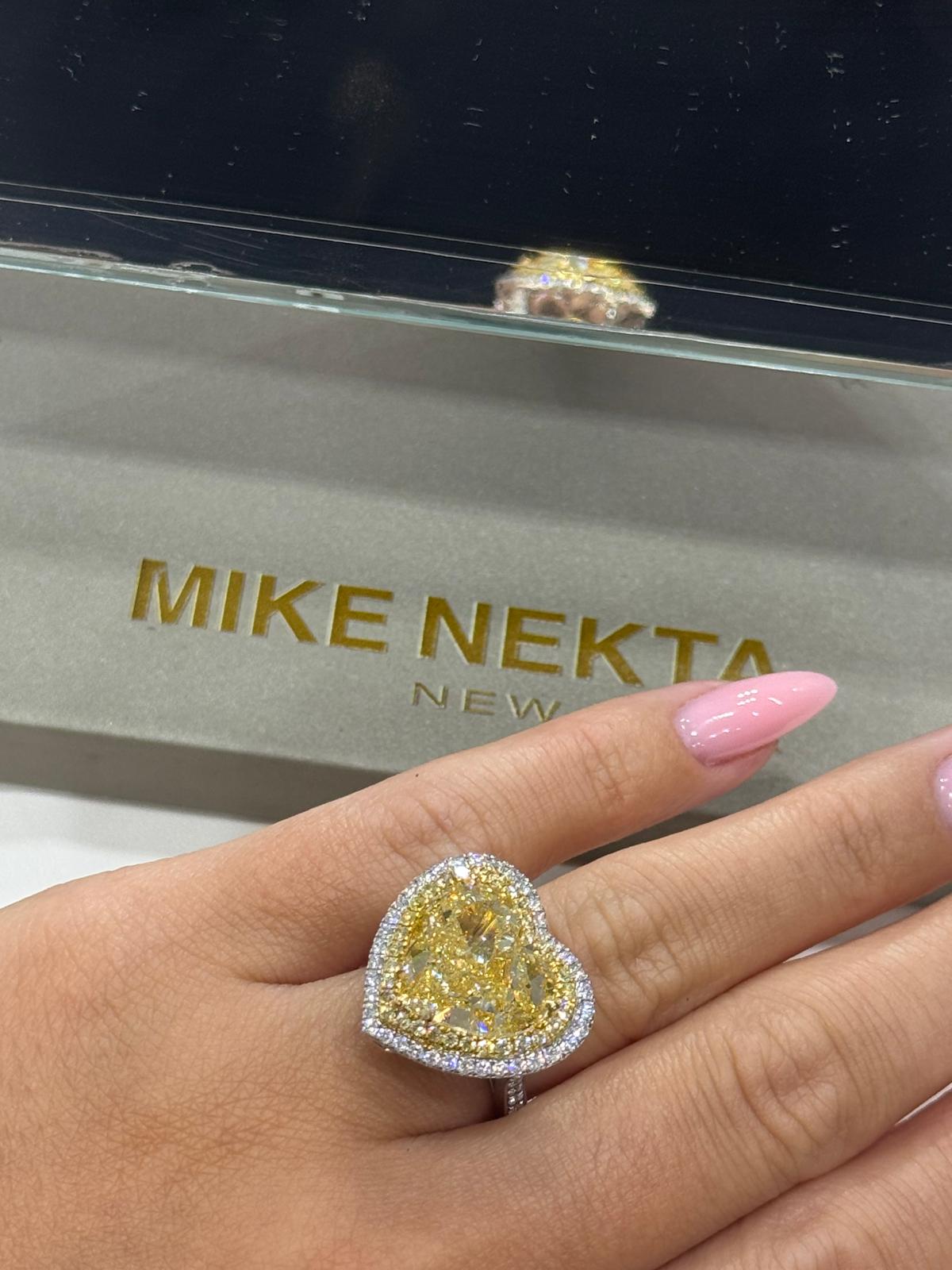 Heart-shaped diamond ring on a hand with 'MIKE NEKTA' jewelry box in the background.