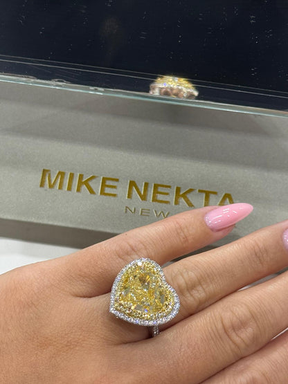 Heart-shaped diamond ring on a hand with 'MIKE NEKTA' jewelry box in the background.