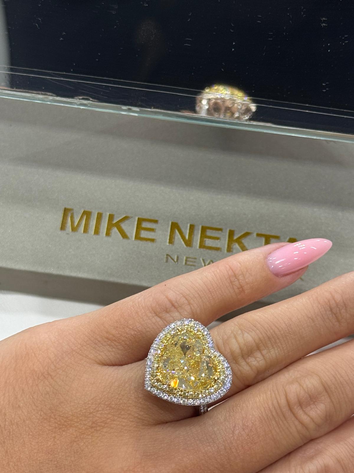 Yellow diamond ring on a hand with 'MIKE NEKTA New York' branding in the background