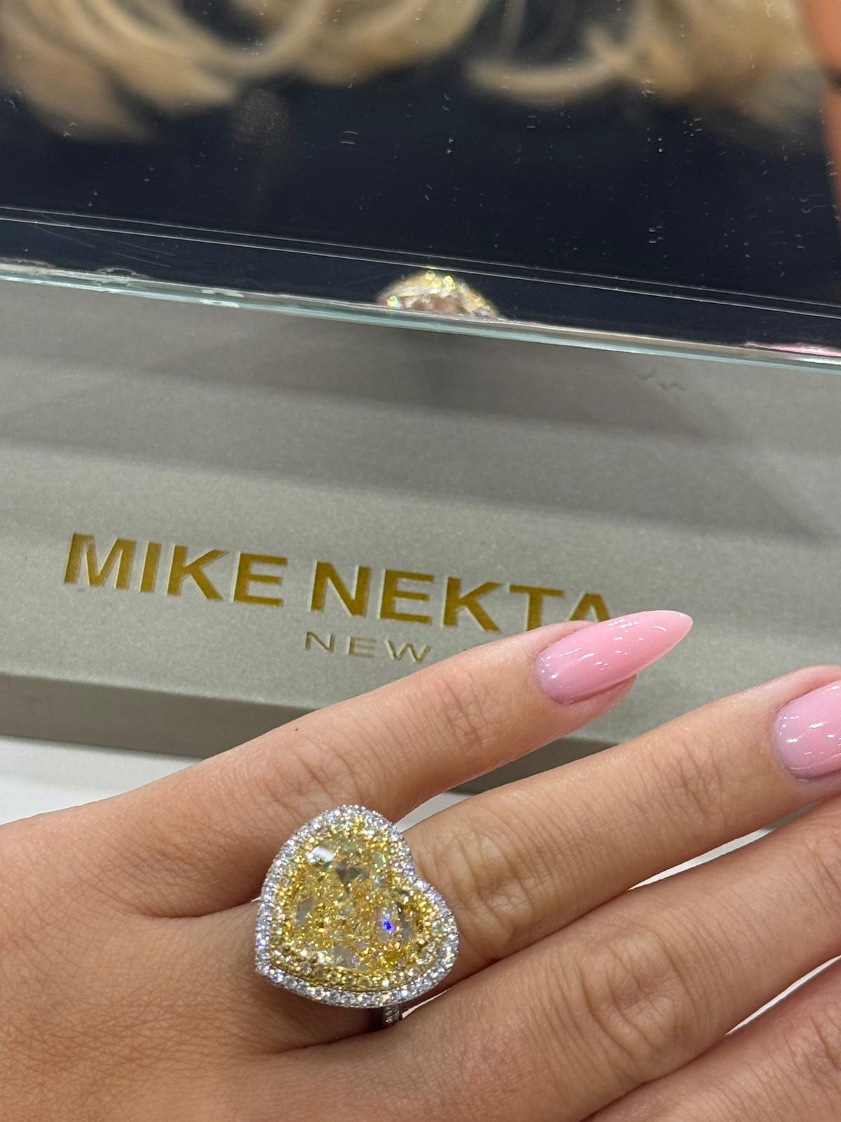 Hand wearing a large diamond ring with 'MIKE NEKTA New York' brand in the background
