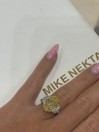 Hand wearing a yellow diamond ring with 'MIKE NEKTA New York' branding in the background