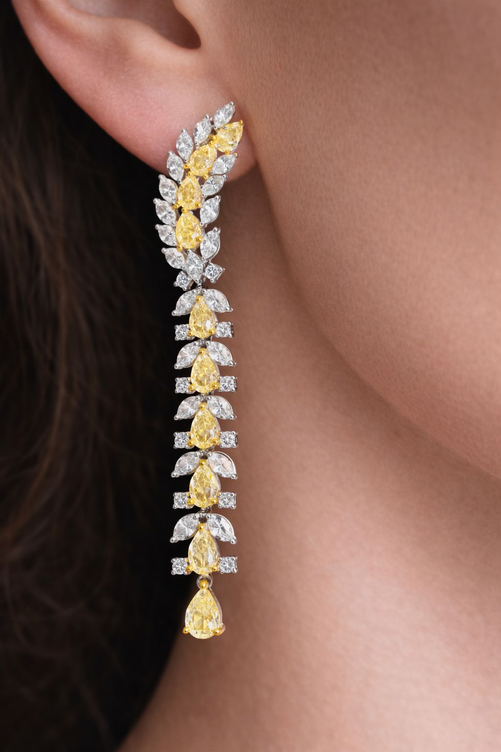 Gold and diamond earring worn on an ear with a blurred background