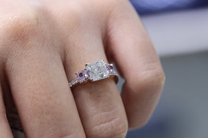 Three stone ring containing Assher Cut and The Center plus Pink Diamond's in the sides on a woman's finger